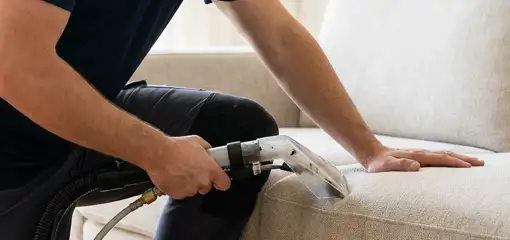 Professional upholstery cleaner deep-cleaning a fabric sofa with a handheld extraction tool, Myrtle Beach, SC.